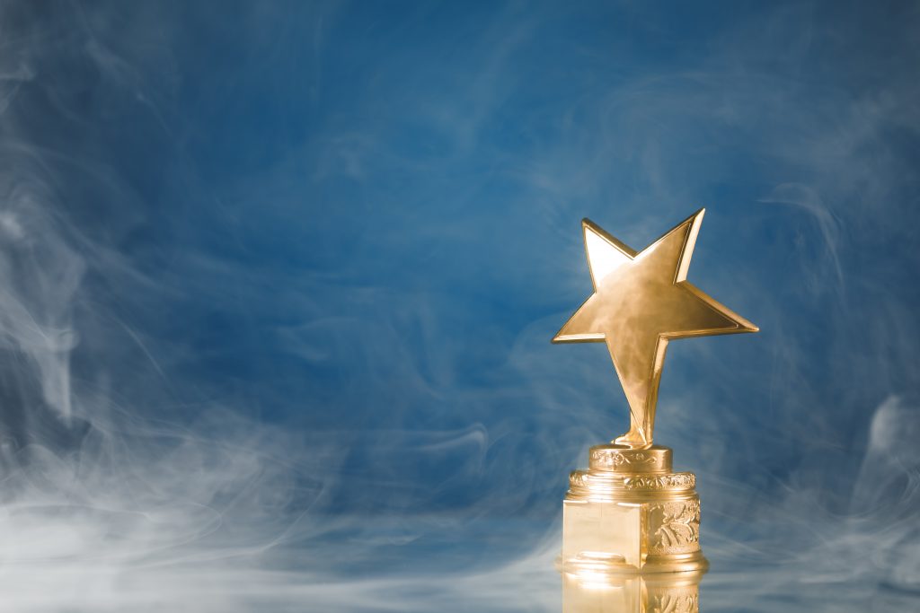 gold star trophy in smoke, blue background