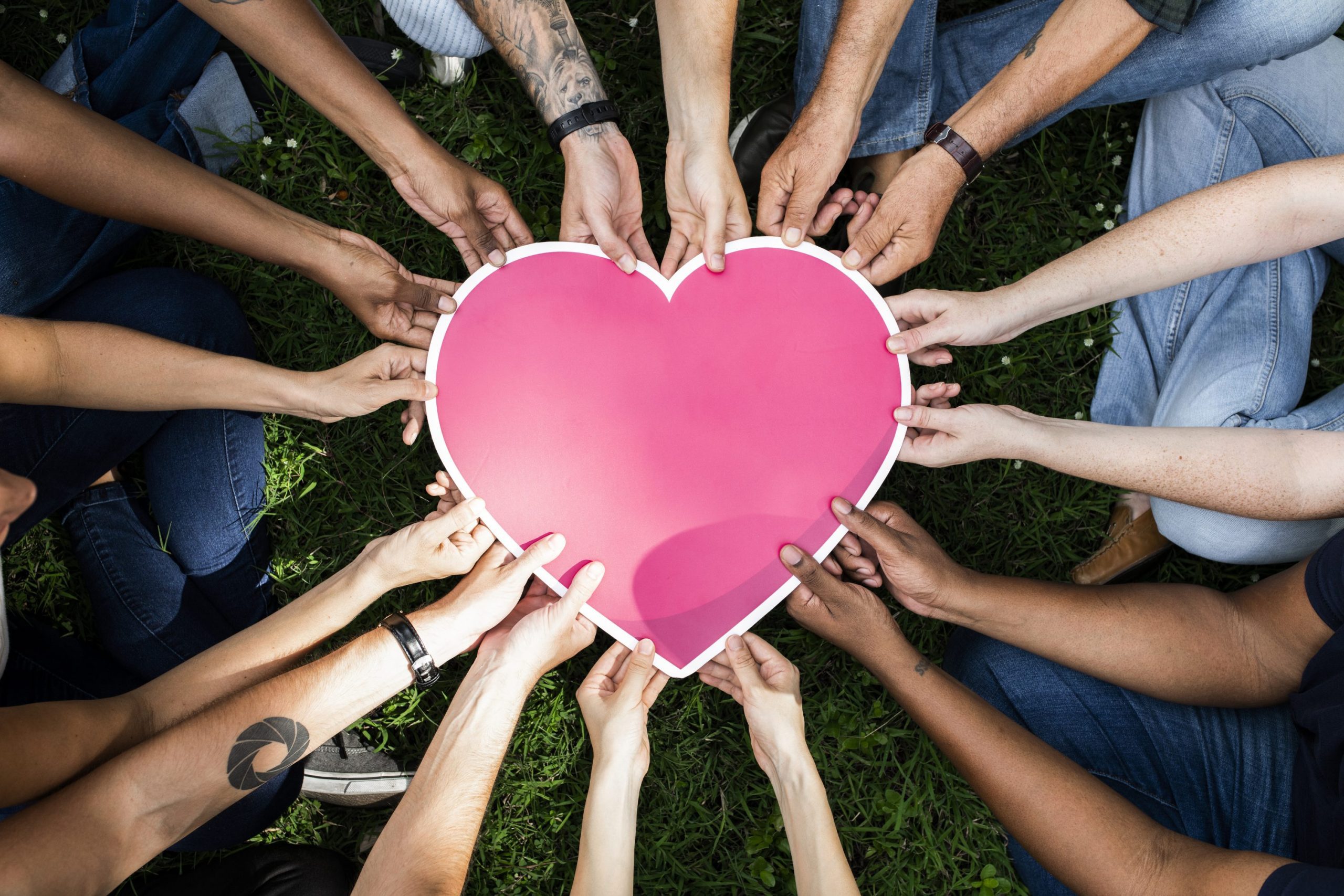 Group of people holding a pink heart icon