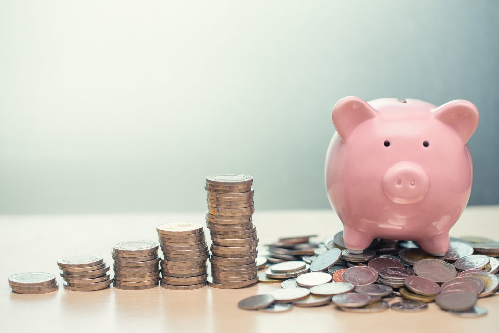 Stacks of coins and a piggy bank to indicate savings